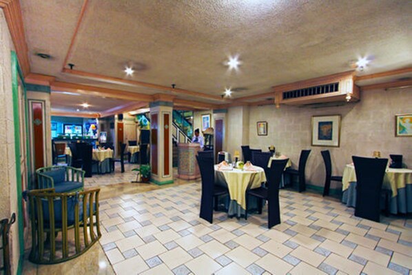A restaurant with a tiled floor, tables with chairs, and a staircase in the background. - Manila Manor Hotel (Manila)