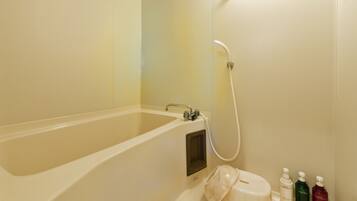 A bathroom with a bathtub, a shower, and a toilet. There are three bottles of toiletries on the counter.