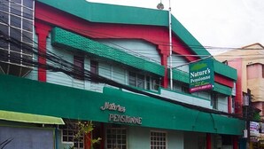 En byggnad med ett grönt solskydd och en skylt med texten ”Naturens pensionat”.