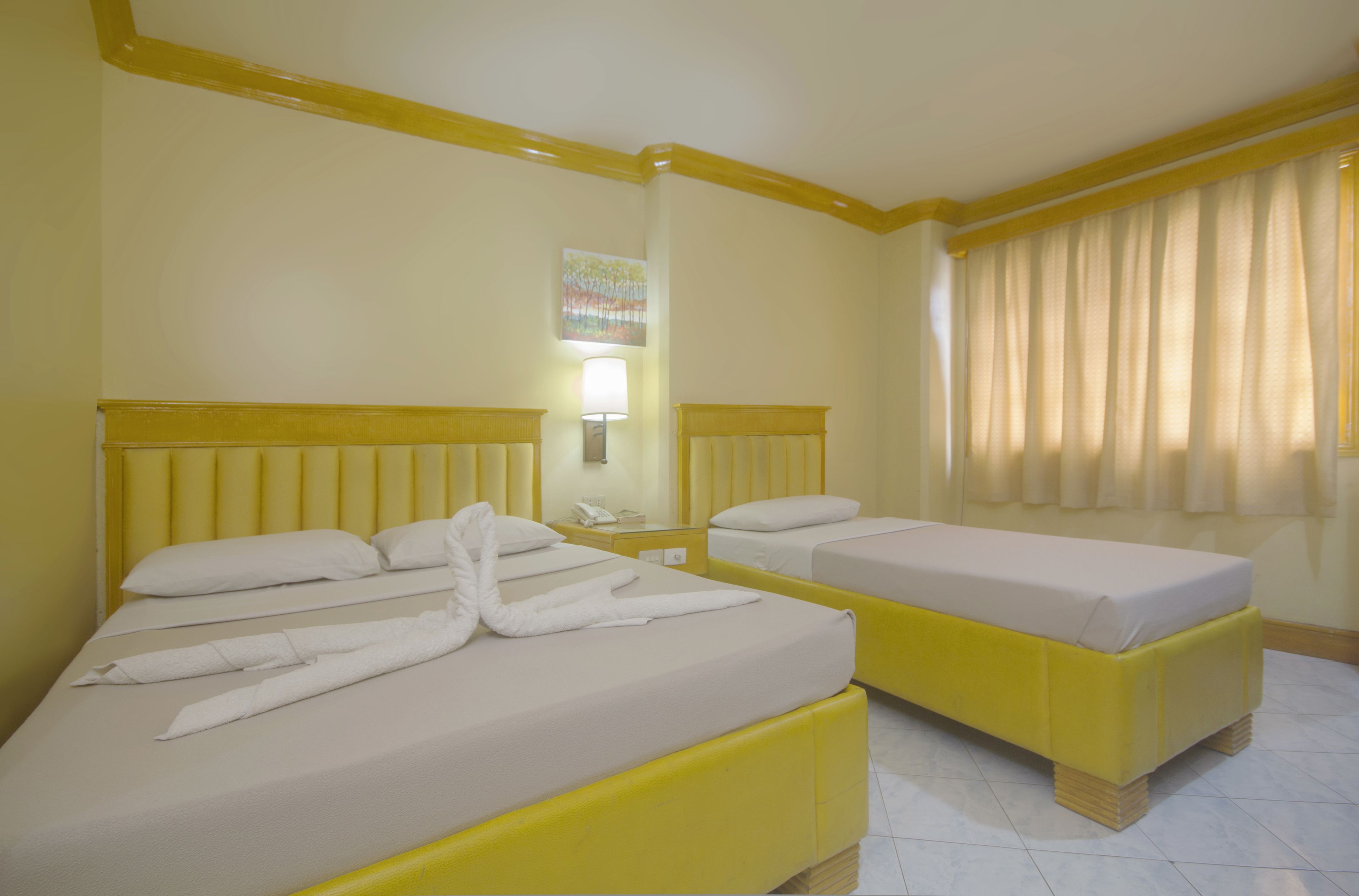 Una habitación de hotel con dos camas, cada una con cabecera y mesita de noche.
