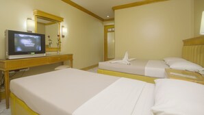 Ett hotellrum med två sängar, en tv på ett skrivbord och en spegel.