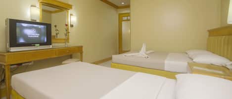 A hotel room with two beds, a TV on a desk, and a mirror.