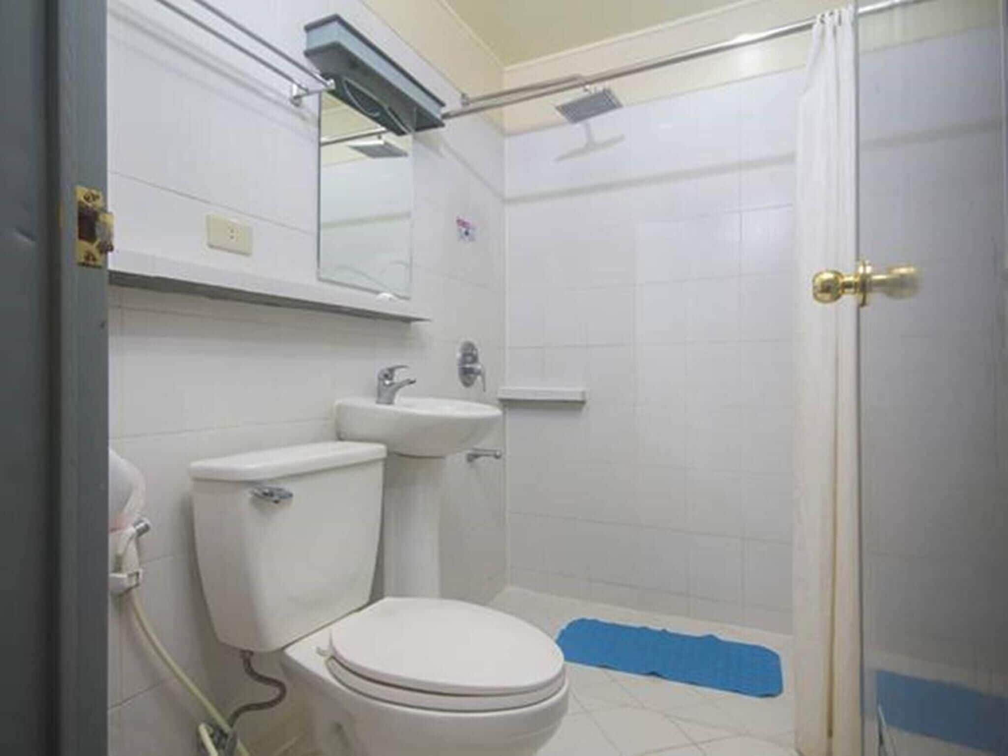 A bathroom with a toilet, sink, and shower area.