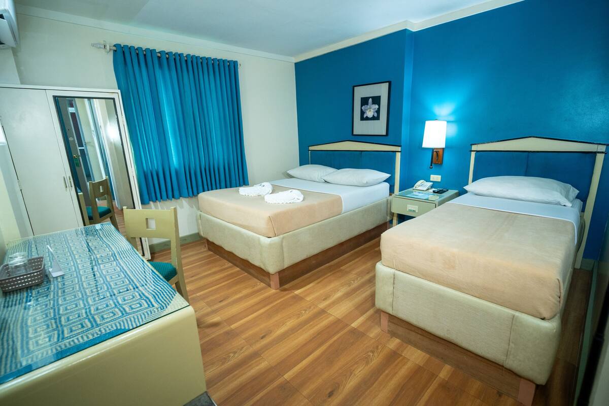 Een hotelkamer met twee bedden, een bureau, een stoel en een spiegel.