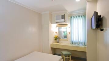 Habitación de hotel con cama, escritorio con espejo, televisión y equipo de aire acondicionado.
