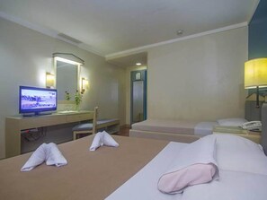 Una habitación de hotel con cama, escritorio, televisor y baño.