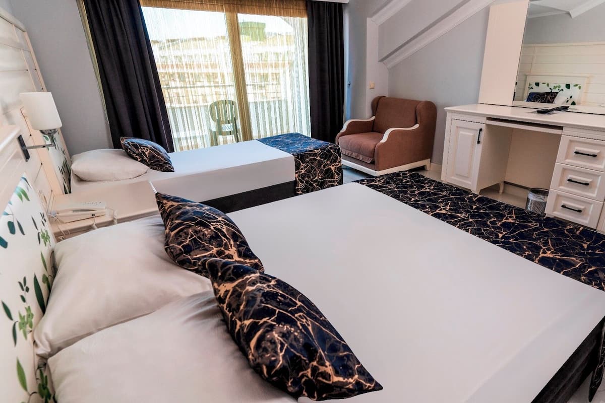 A hotel room with a bed, a desk, a chair, and a TV.