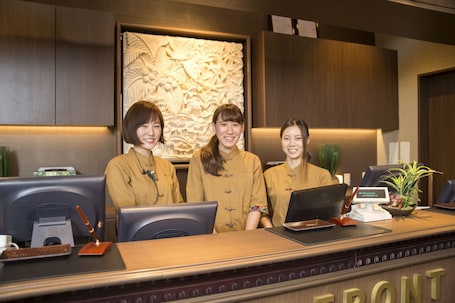 A reception desk with three staff members, a computer, and a plant.