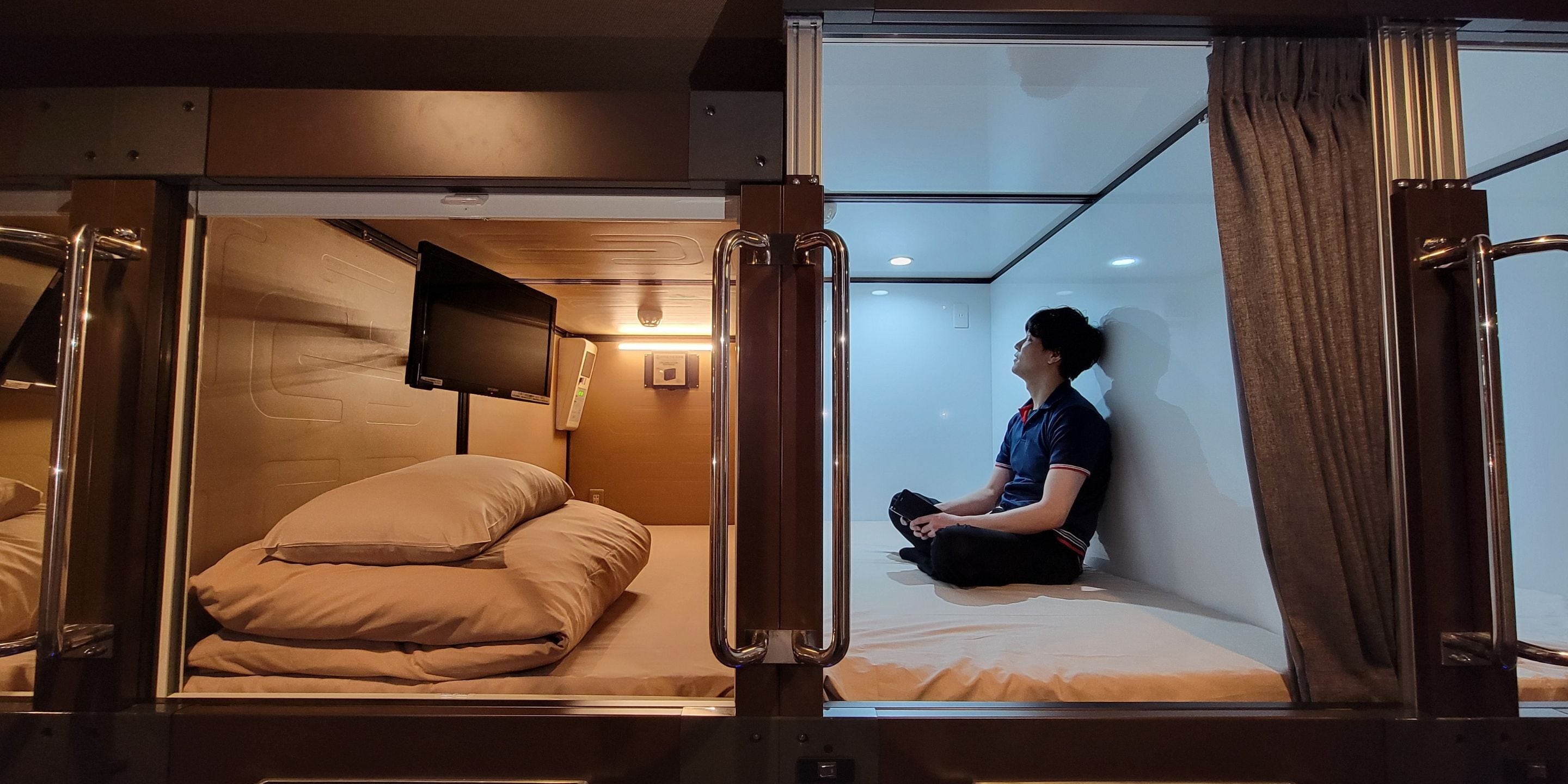A compact, modern room with a single bed, a mounted television, and a small bedside table.