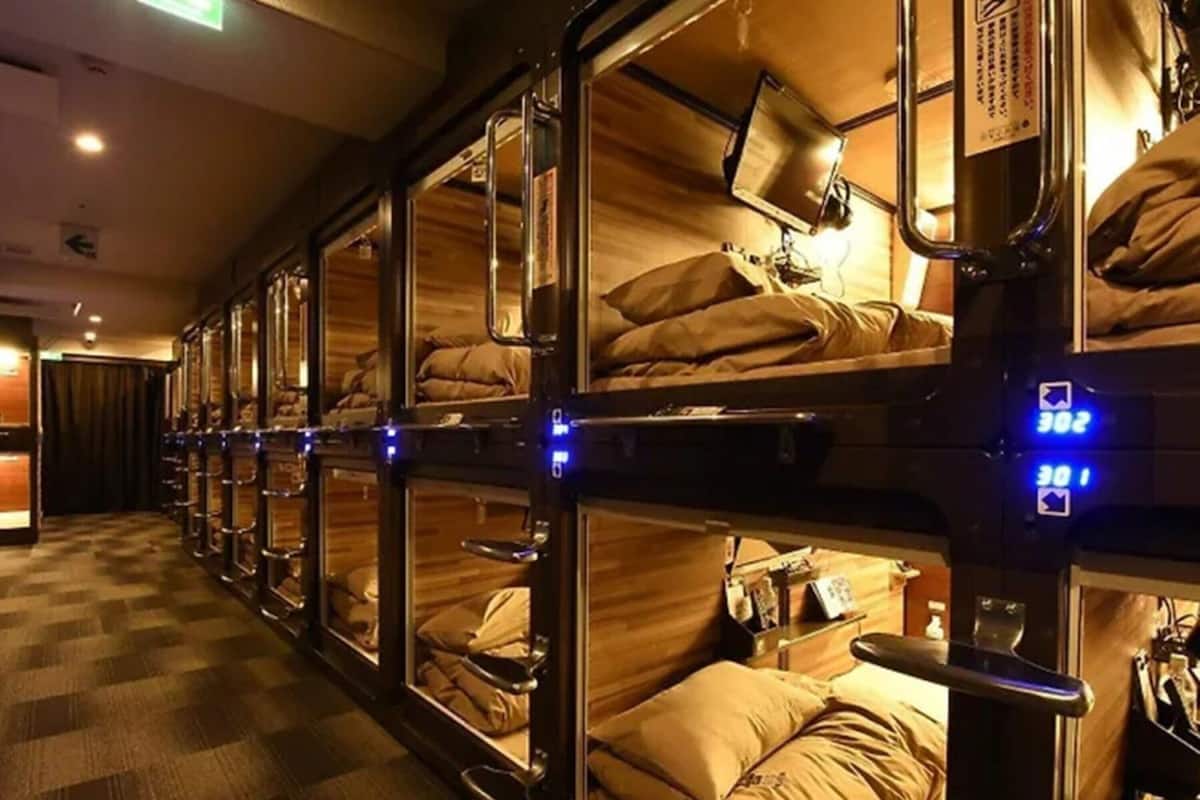 A row of bunk beds with individual headboards and a control panel with illuminated buttons.