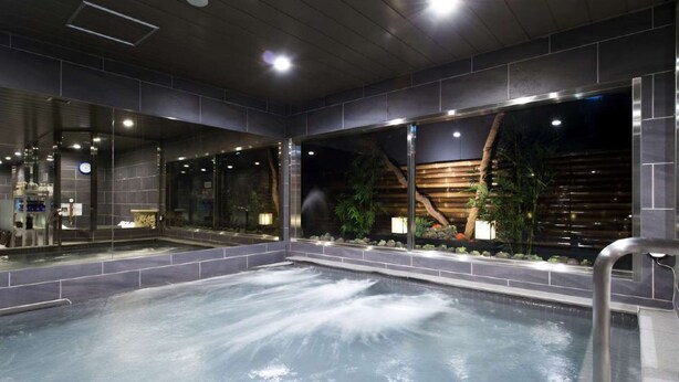 A spa area with a hot tub, glass walls, and a wooden wall with plants.
