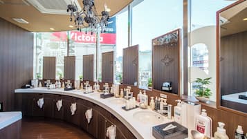A modern bathroom with multiple sinks, mirrors, and a chandelier.