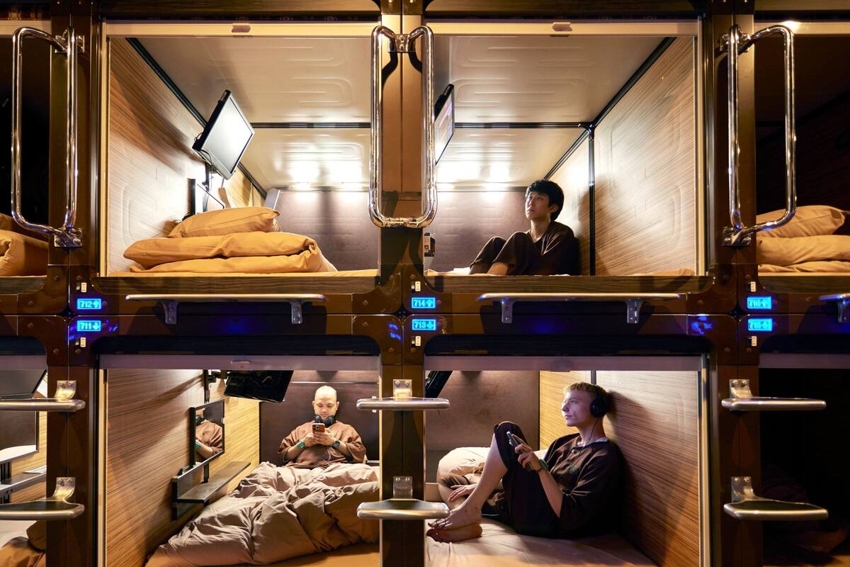 Un compartiment de train équipé de lits superposés, chacun ayant une petite table et un téléviseur.