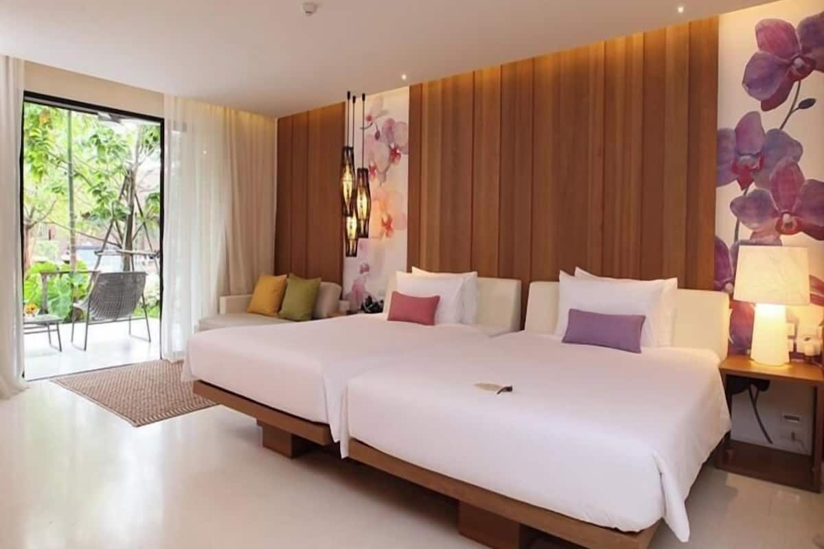 Habitación de hotel moderna con dos camas, vista a zonas verdes y una pared de acento de madera.