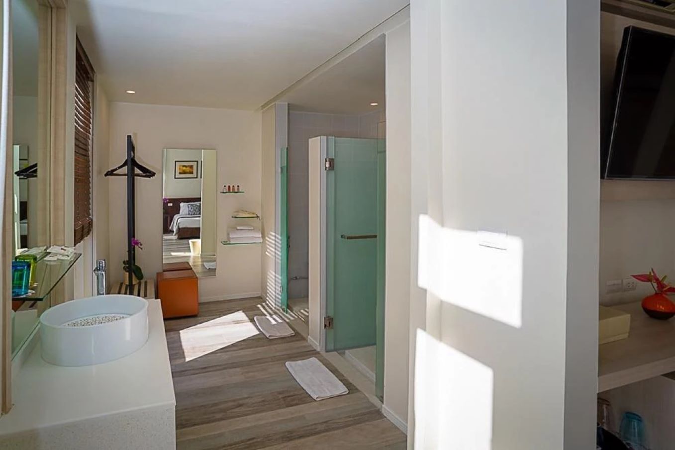 Habitación de hotel moderna con un baño amplio, una cama con vistas y un televisor montado en la pared.