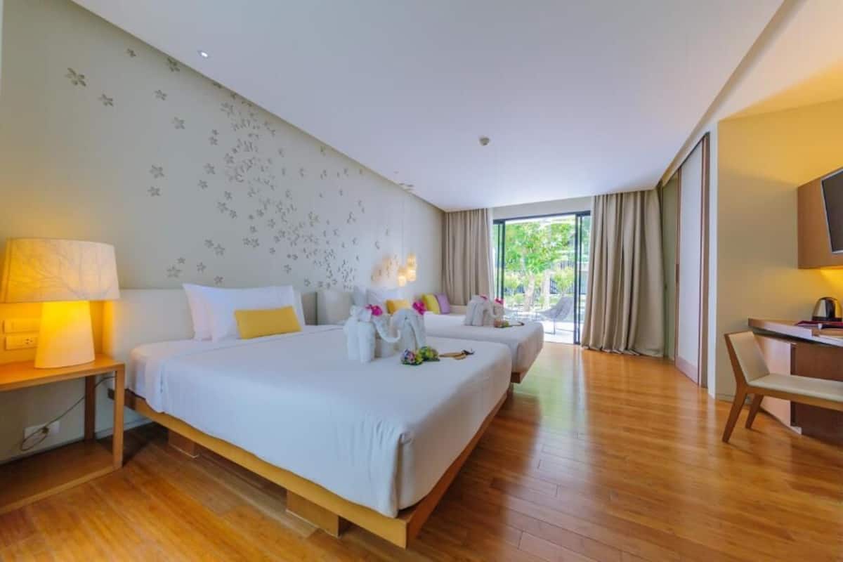Habitación de hotel con dos camas, un escritorio y un ventanal grande.