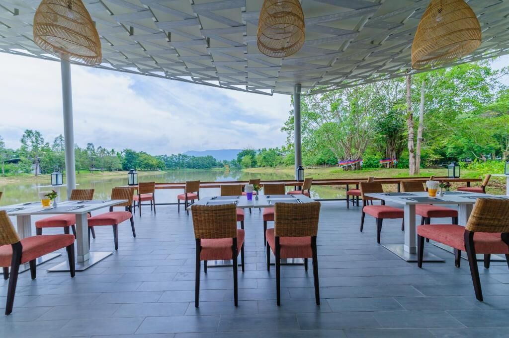 An outdoor dining area with tables and chairs, a view of a lake, and a covered seating area with a view of the surrounding landscape.