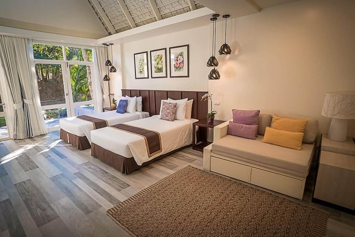Un dormitorio amplio con dos camas, un sofá y un ventanal con cortinas.