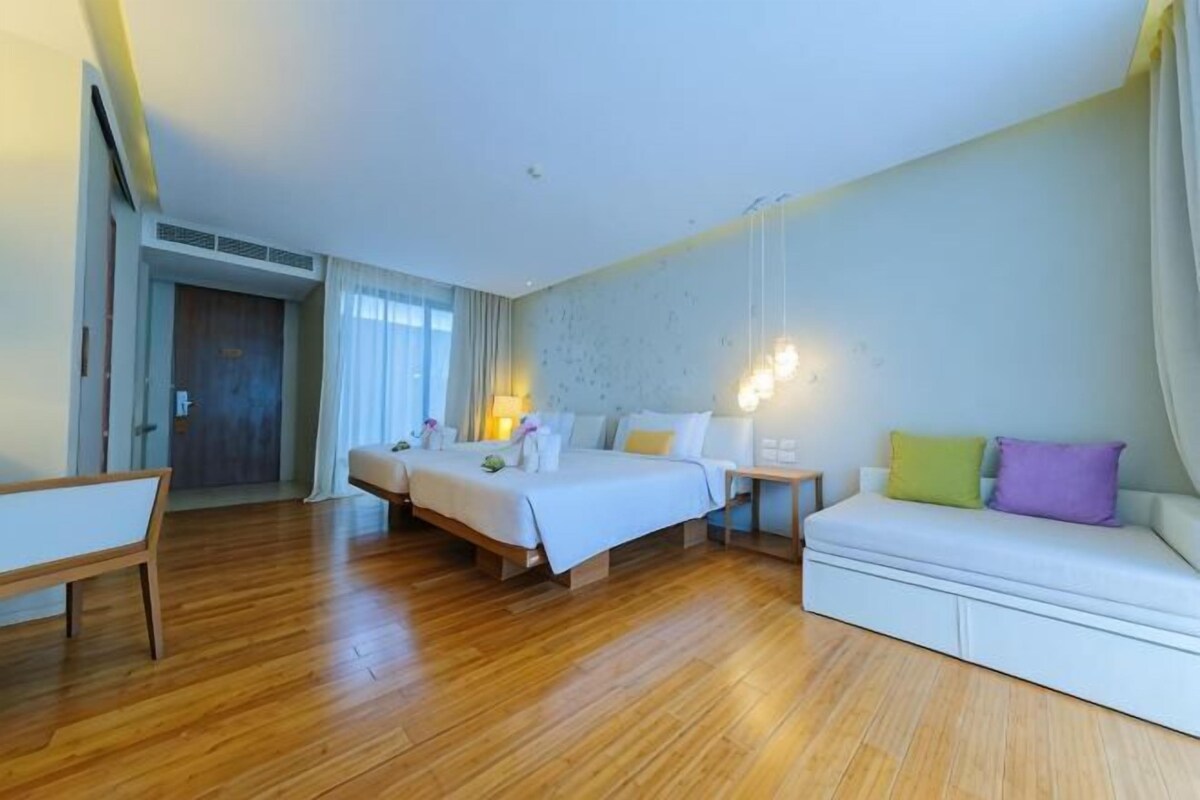 A hotel room with two beds, a sofa, a desk, and a chair.