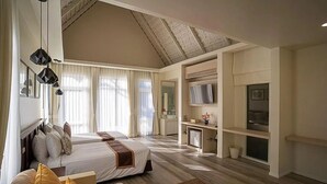 Una habitación de hotel con una cama grande, un escritorio, un televisor y una kitchenette.