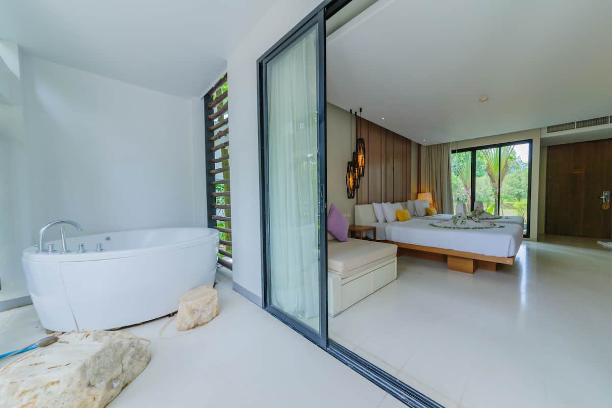 Un baño moderno con una bañera blanca grande, un estante de madera y una piedra en el suelo.