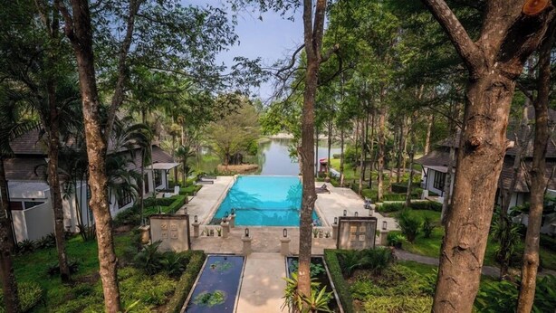 Un resort con piscina central, rodeado de exuberante follaje y árboles.