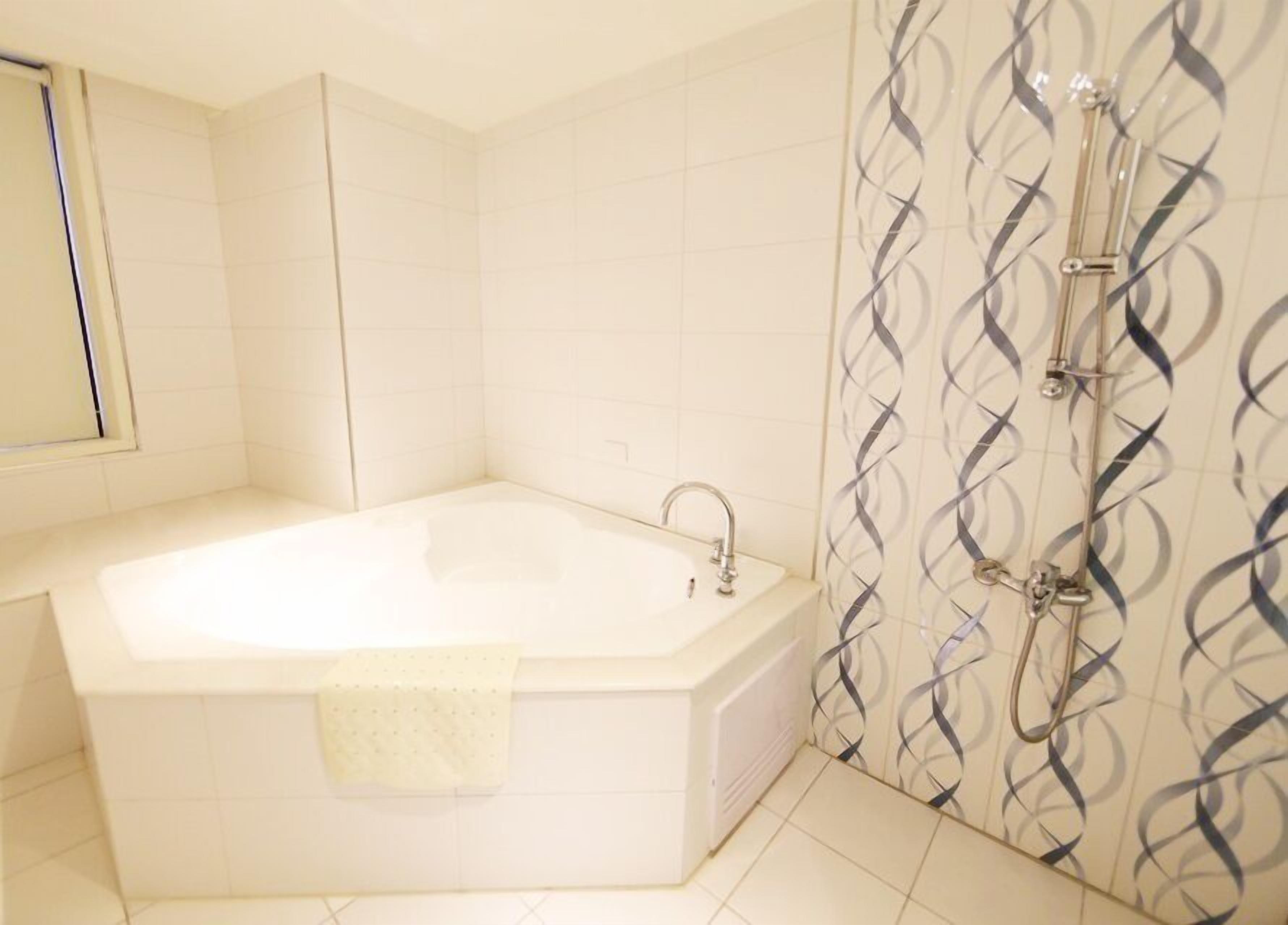 Un baño con bañera, ducha y espejo.