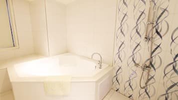 Un baño con bañera, ducha y espejo.