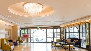 A spacious lobby with a chandelier, comfortable seating, and large windows offering a view of the street. - Grand Earl Hotel (Douliou)