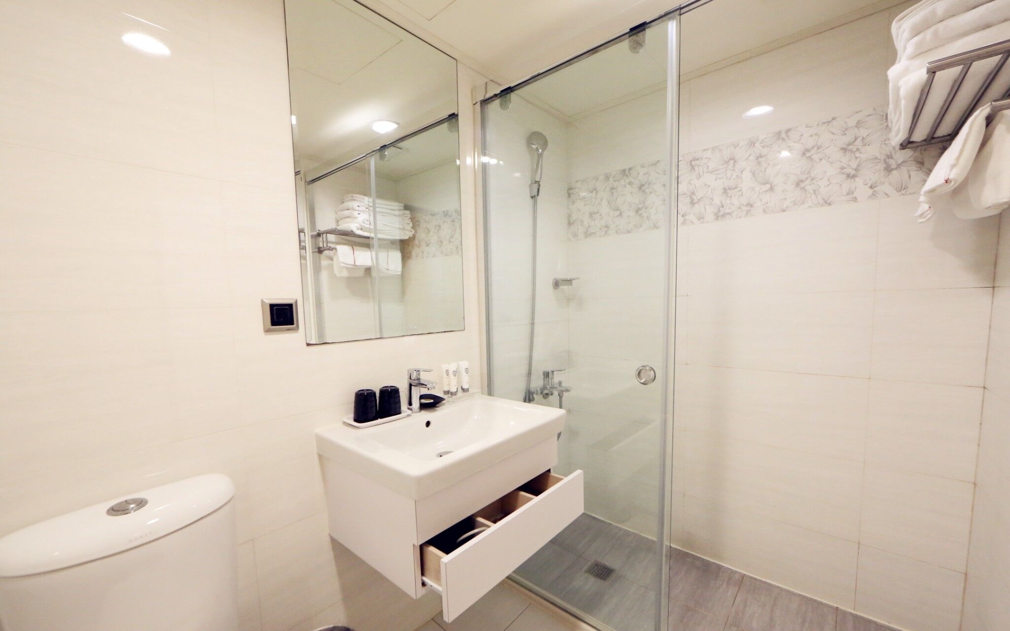 A modern bathroom with a glass-enclosed shower, a white sink with a mirror, and a toilet.