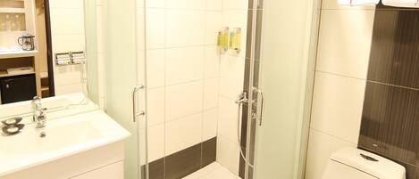 Un baño moderno con ducha de vidrio, un lavabo blanco con espejo y un inodoro.