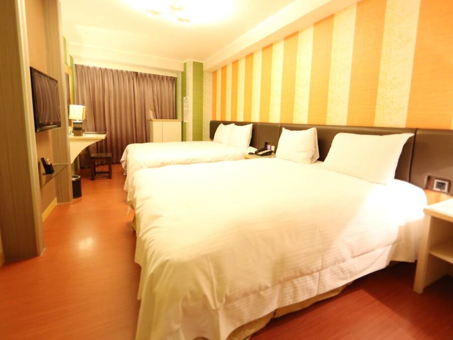 A hotel room with two beds, a television, a desk, and a lamp.