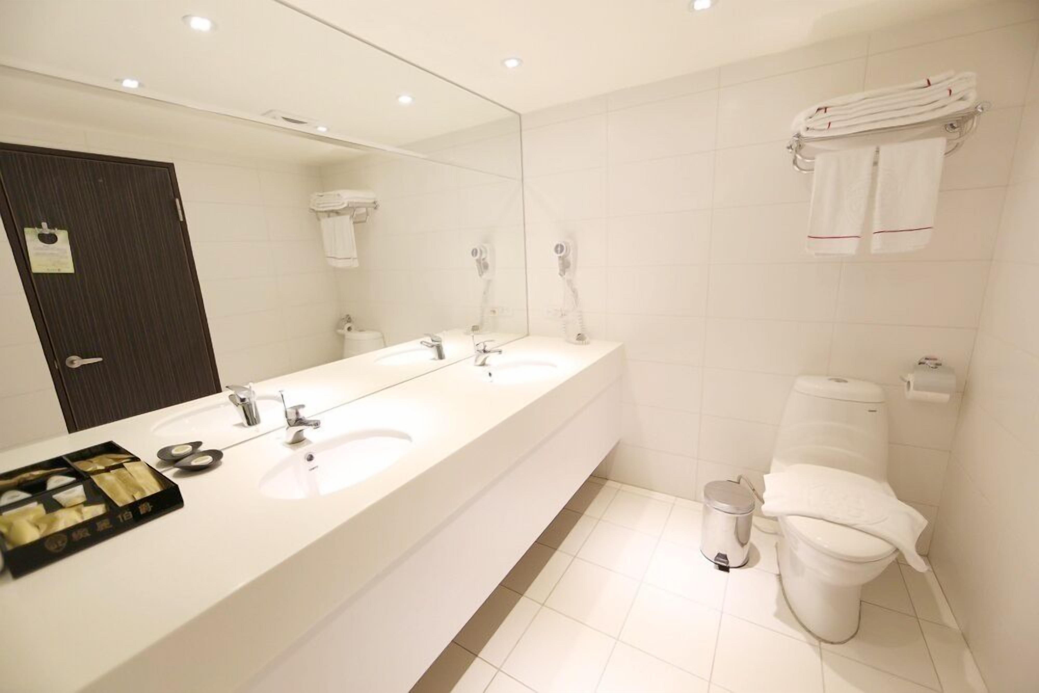 Een moderne badkamer met twee wasbakken, een grote spiegel en een toilet.