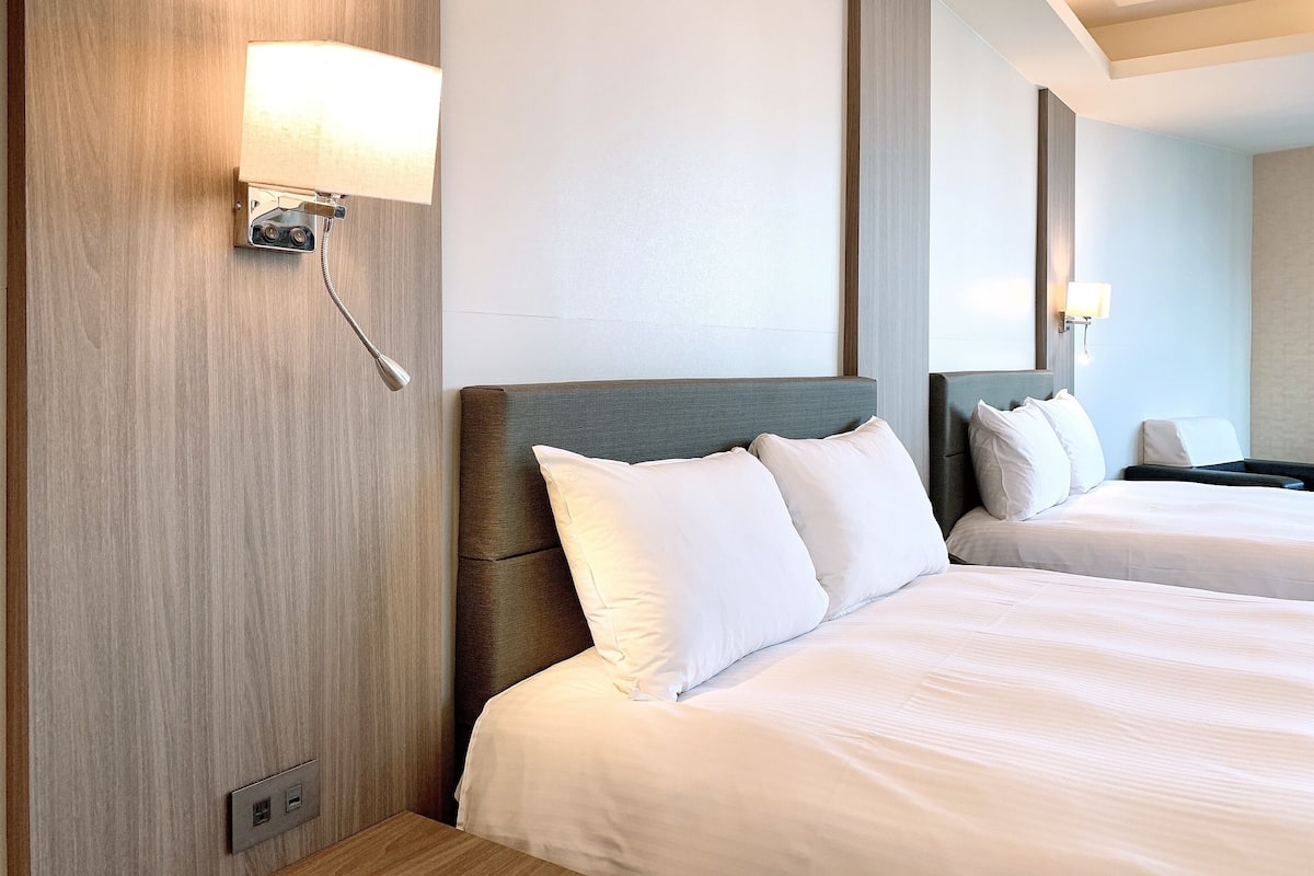 Een hotelkamer met een groot bed, een nachtkastje, een lamp en een spiegel.