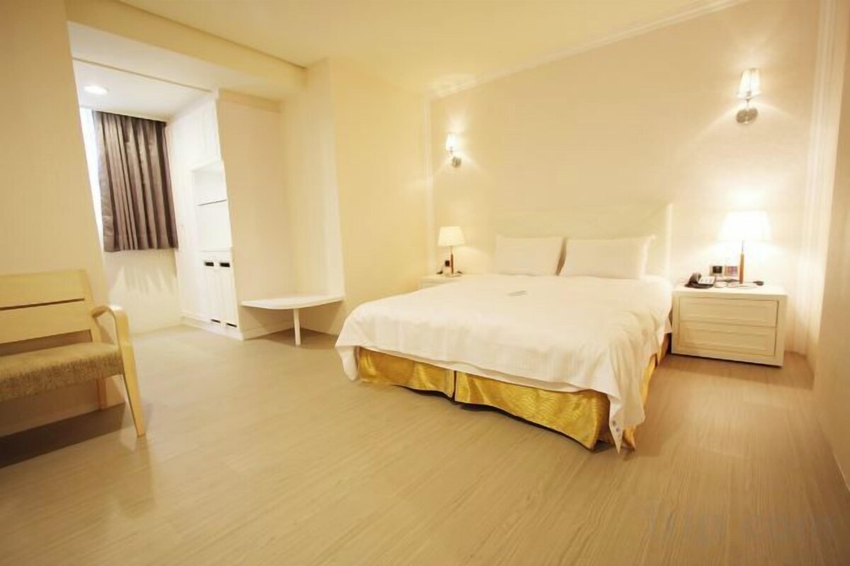 Una habitación de hotel con una cama grande, una mesita de noche y una silla.