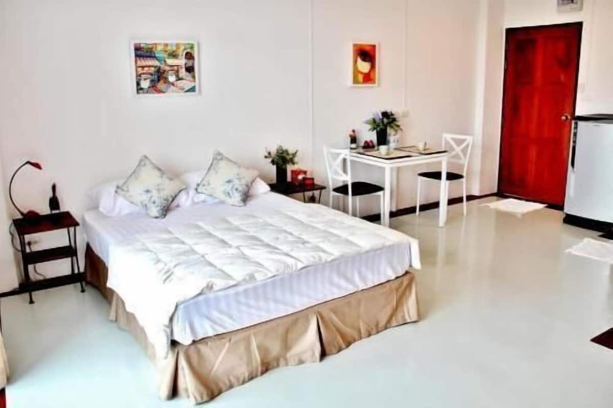 Ein Schlafzimmer mit Bett, Nachttisch, Stuhl, Schreibtisch und einer roten Tür.