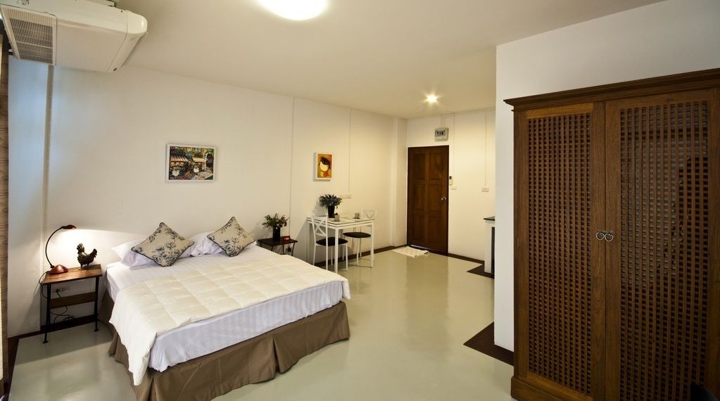 A bedroom with a bed, bedside table, lamp, and a wooden wardrobe.