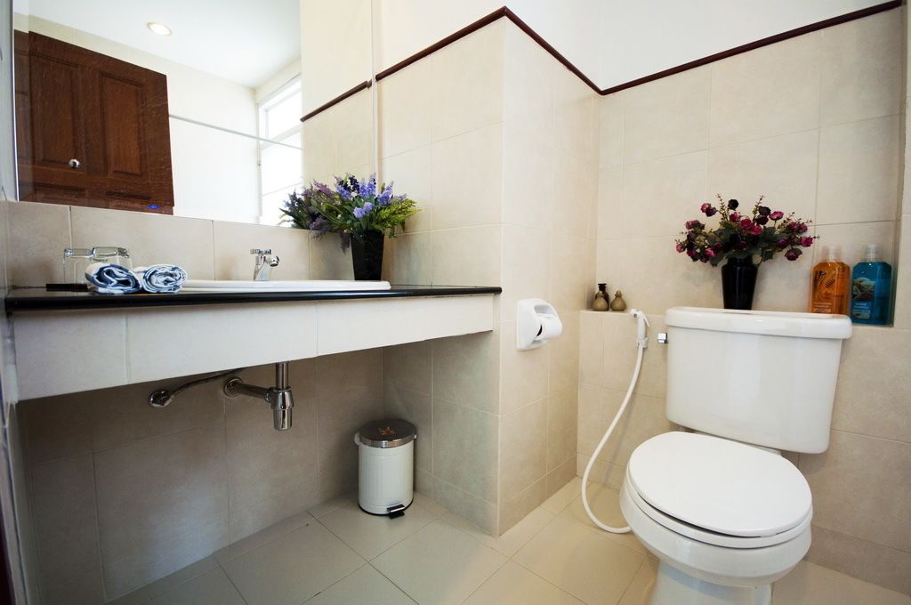 A bathroom with a toilet, sink, and two flower vases.