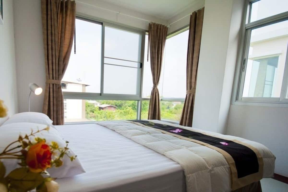 Ein Hotelzimmer mit Bett, Vorhängen, einem Fenster und Blick auf Grünfläche.