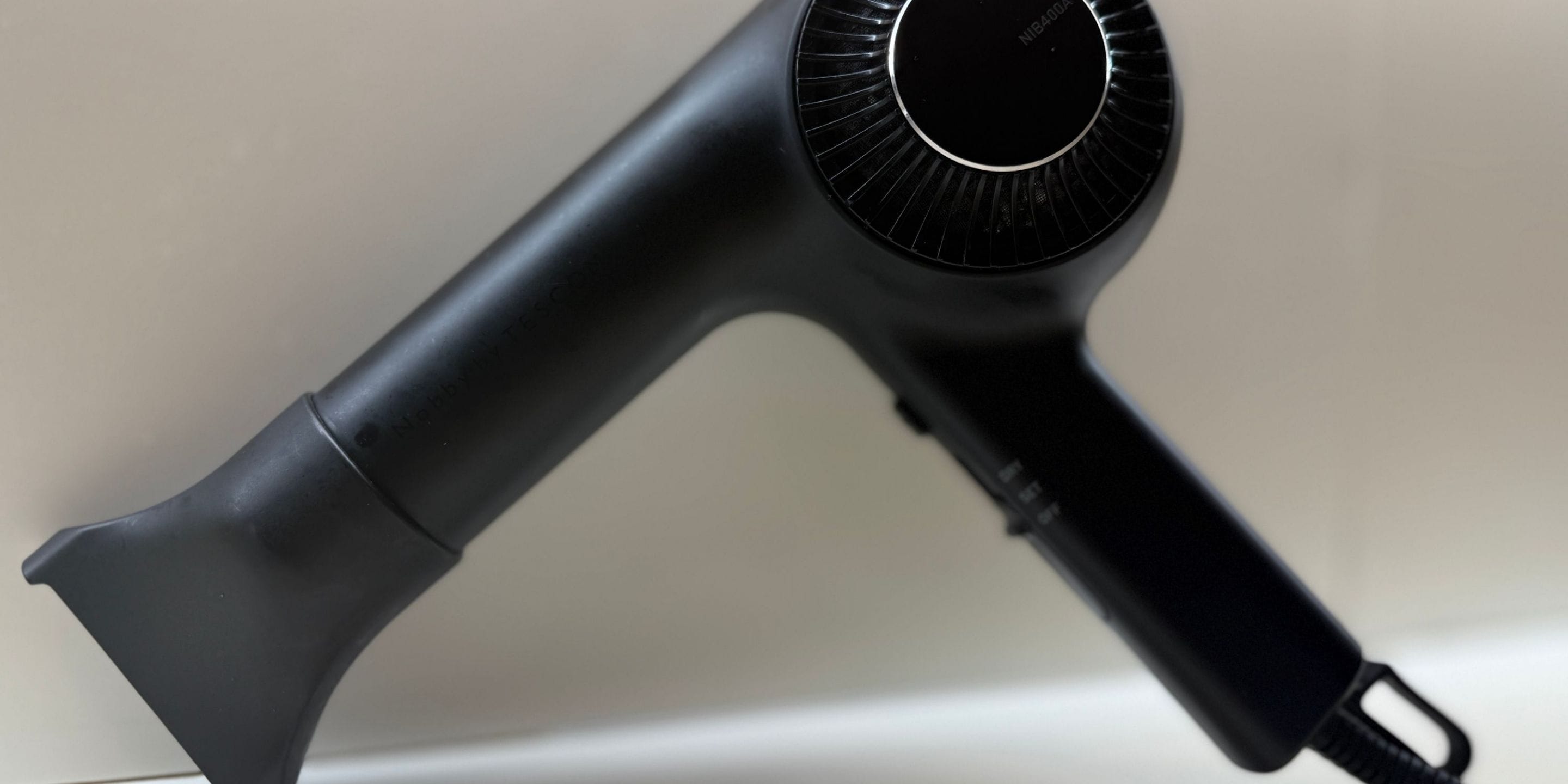 A black hairdryer with a circular nozzle and a flexible hose.