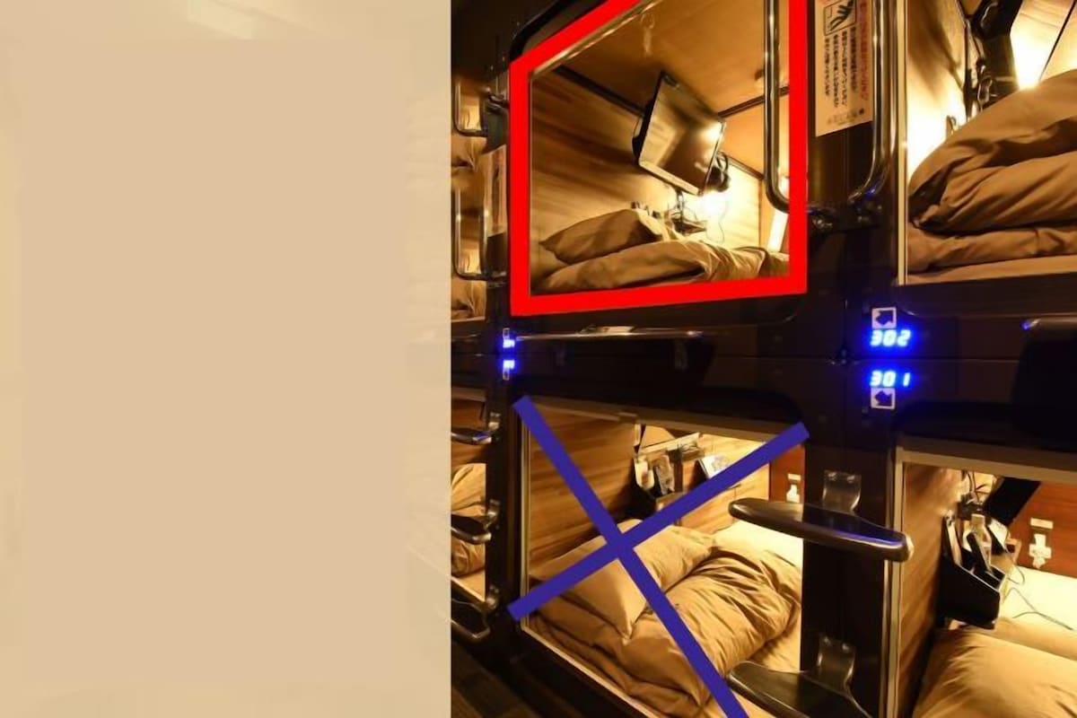 A bunk bed room with a red frame, a bedside table, and a small shelf.