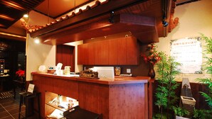 A reception desk with a wooden counter, a digital display, and a small seating area with a chair.