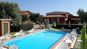 En sÀsongsöppen utomhuspool, parasoller och solstolar