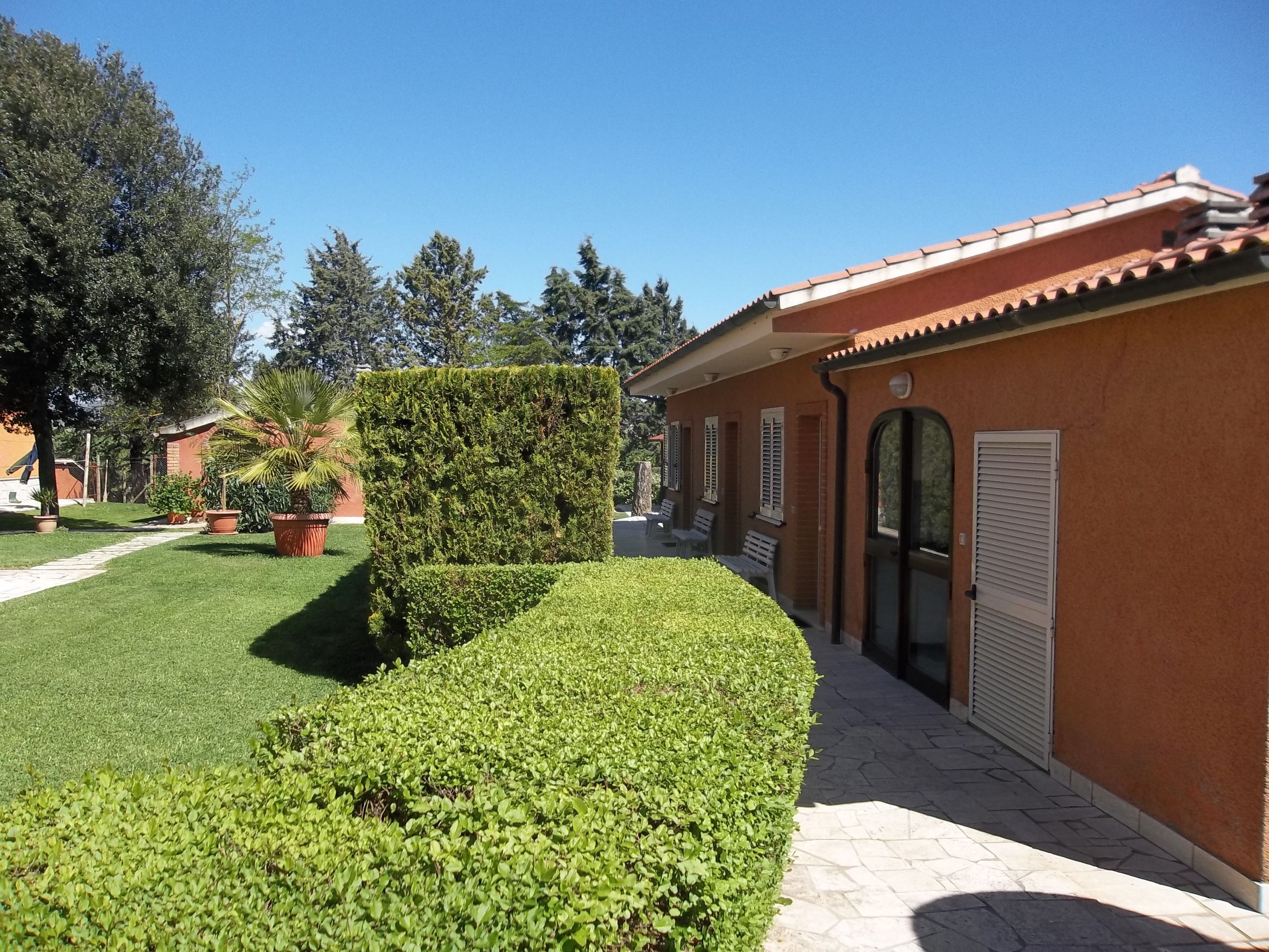 A building with a tiled roof, a well-maintained lawn, and a hedge.