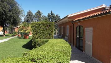 A building with a tiled roof, a well-maintained lawn, and a hedge.