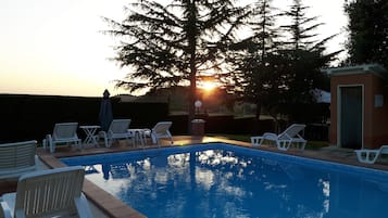 En sÀsongsöppen utomhuspool, parasoller och solstolar