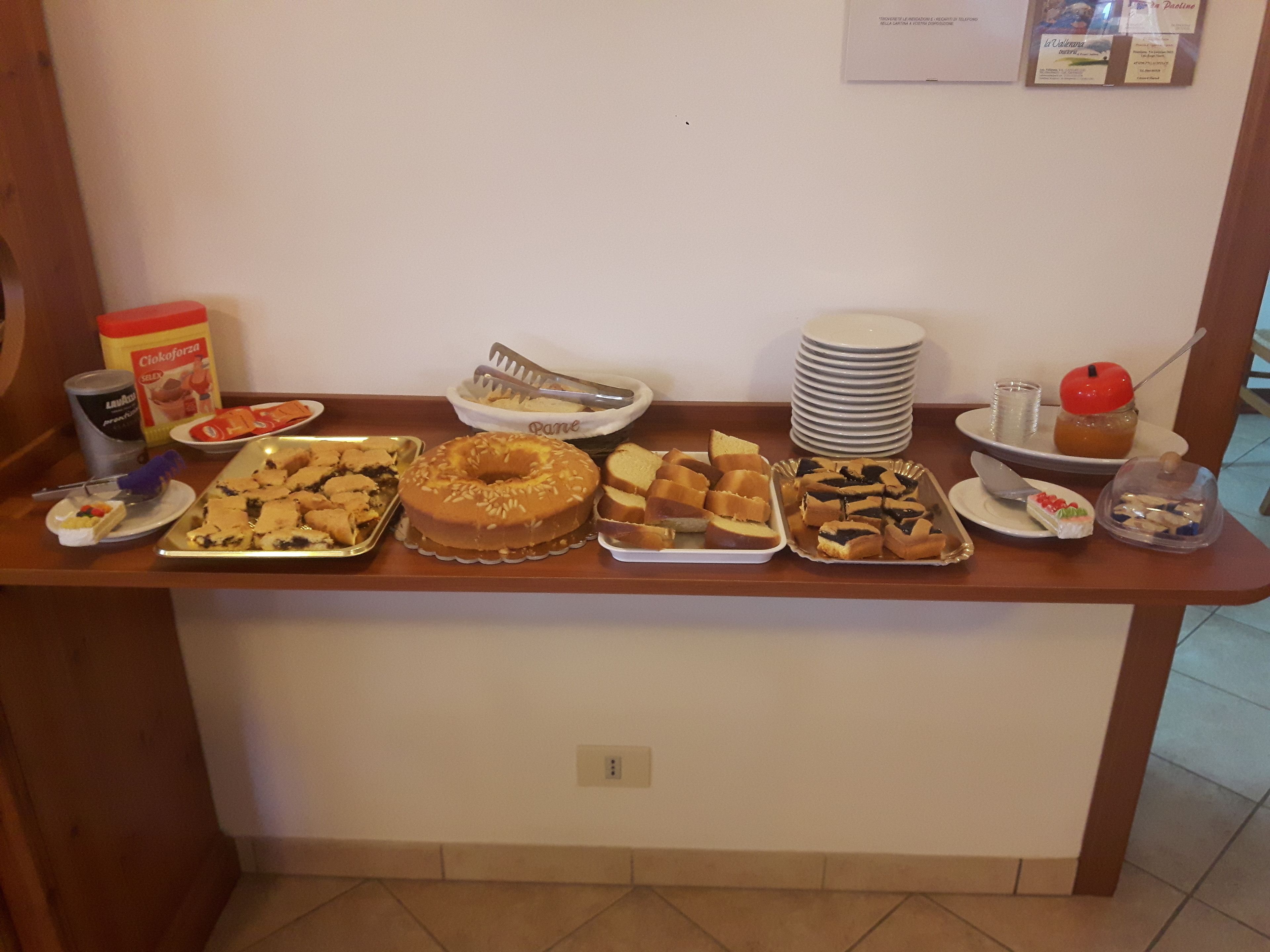 Een buffet met diverse gerechten, waaronder taarten, gebak en een donut.