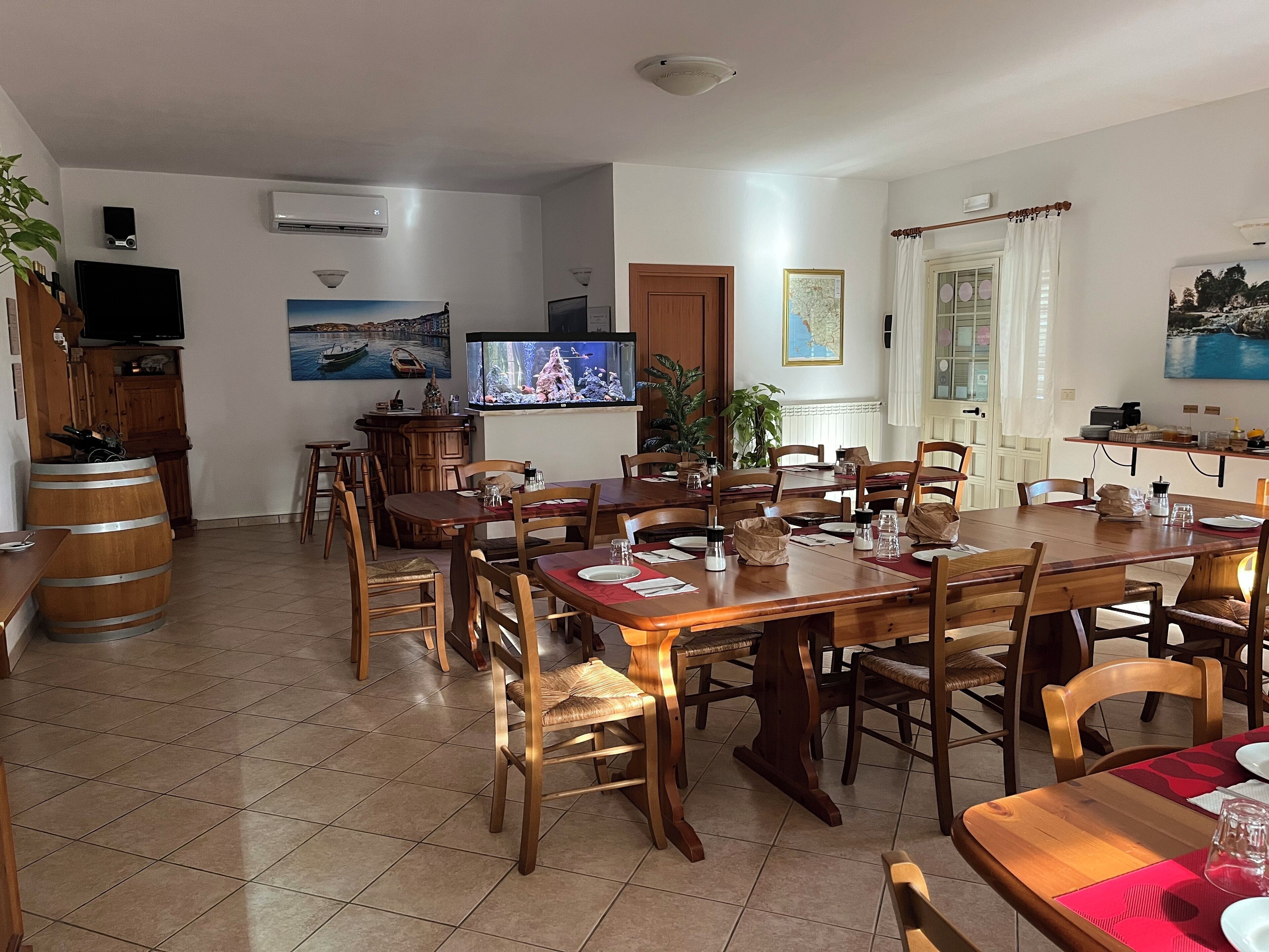 A dining area with wooden tables and chairs, a television, and a large aquarium.