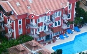 A multi-story building with balconies, a swimming pool, and lounge chairs. - Red Rose Hotel (Fethiye)