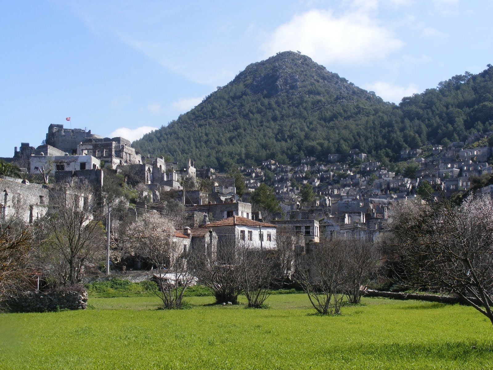 A historic town with stone buildings, a prominent hill, and a clear sky.